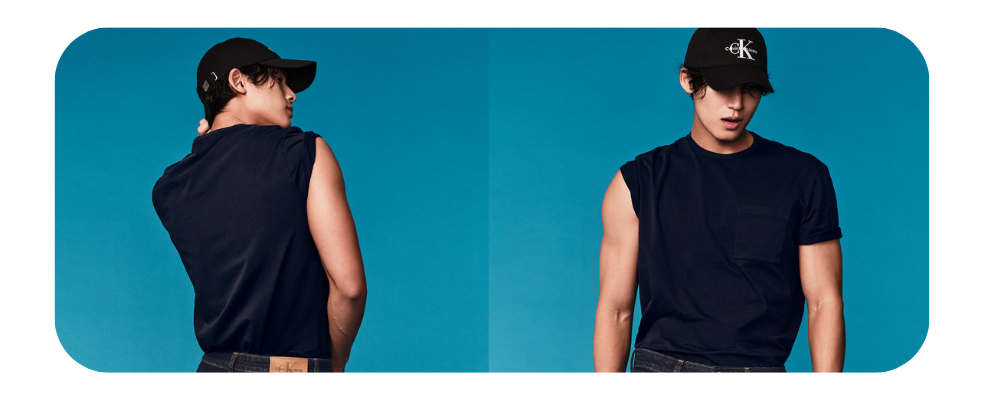 Man wearing a navy blue sleeveless t-shirt and a black Calvin Klein baseball cap.