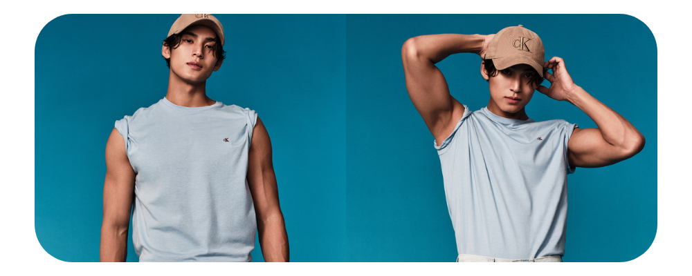 Man wearing a light blue sleeveless Calvin Klein t-shirt and a tan CK baseball cap.