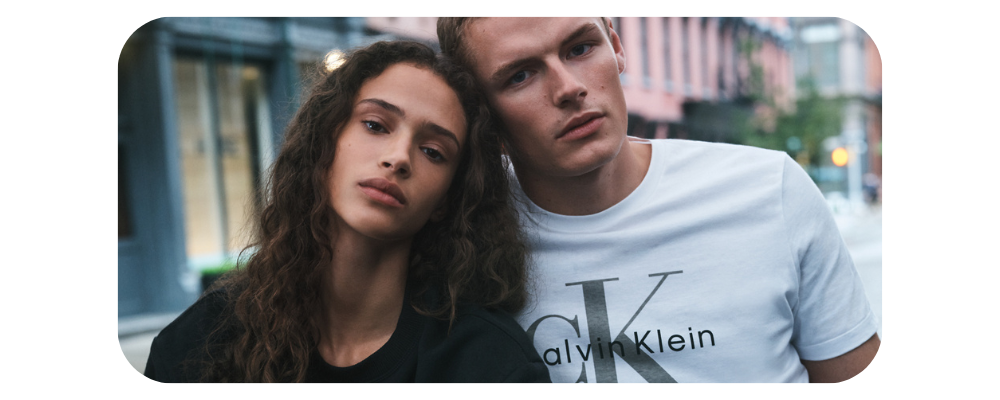A man wearing a white Calvin Klein t-shirt and a woman in a black top posing together.
