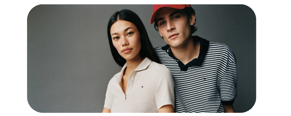 A couple posing in Tommy Hilfiger apparel: a white polo shirt and a striped navy polo shirt.