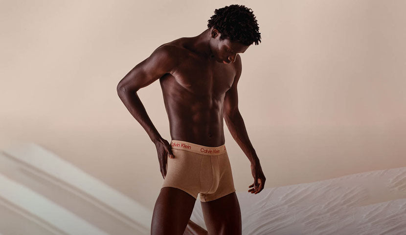 Muscular man wearing tan Calvin Klein men's underwear against a neutral background.